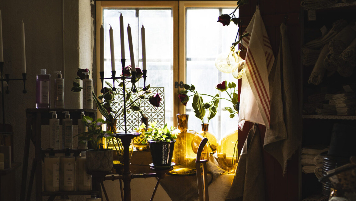 Gyllenbruna glasvaser, kronljus, kökshanddukar och andra inredningsprylar blir upplysta av ett fönster i gammal stil.