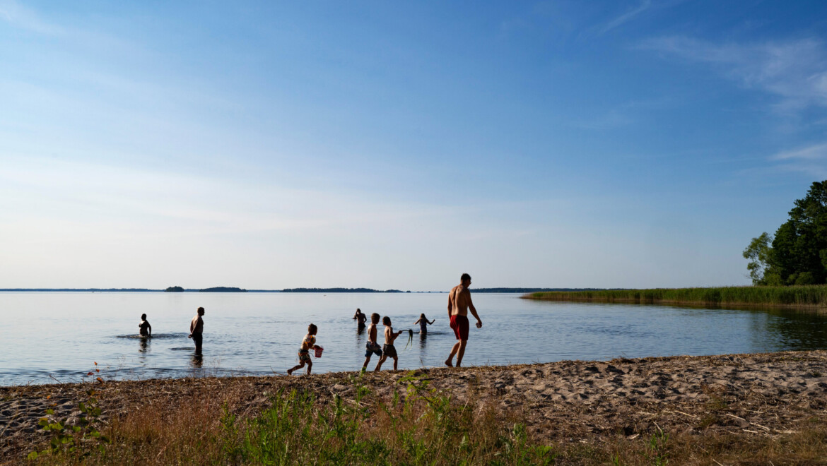 Badplats med sandstrand och gräs.
