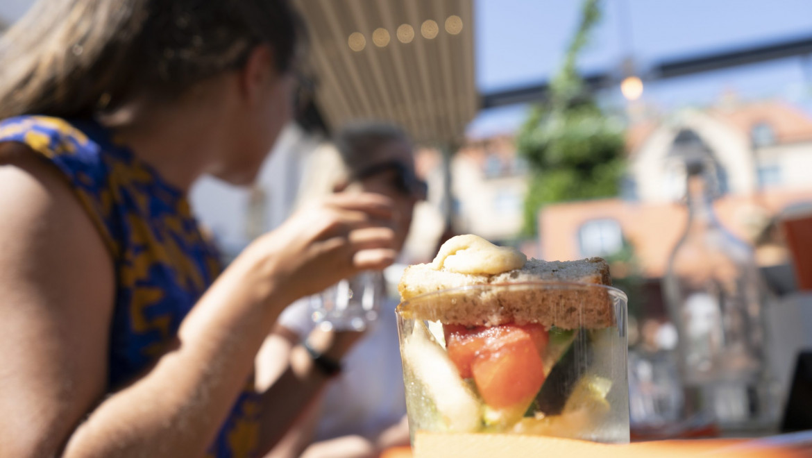En kvinna i kortärmat håller upp handen ovanför ett glas med grönsaker i.