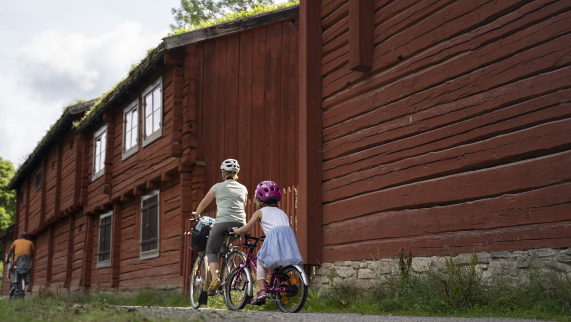 Två röda timmerhus och två cyklister.