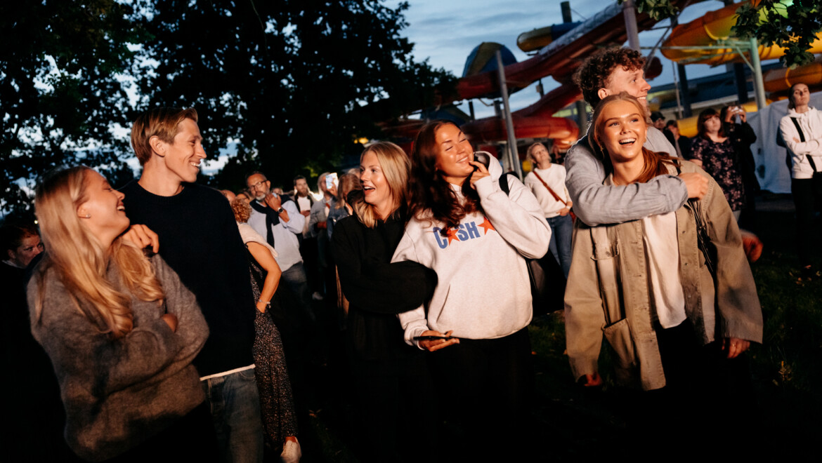 Sex unga vuxna som hänger i kvällsmiljö och tittar bortom kameran.