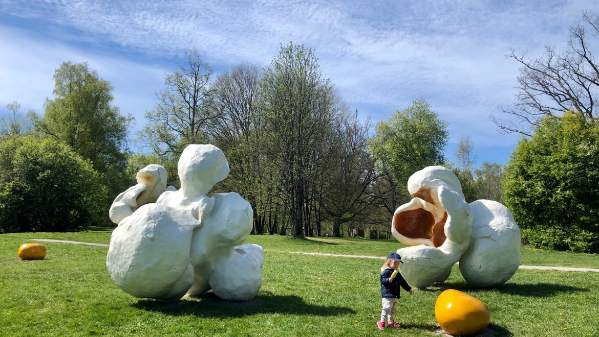 En liten flicka står framför statyer av popcorn i en park.