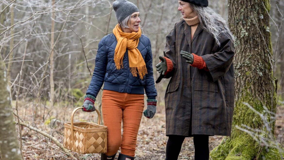 Två äldre kvinnor är höstklädda och går i skogen.