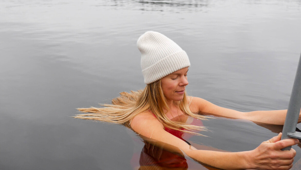 Närbild på Annika Harrsjö som vinterbadar med vit mössa och röd baddräkt.