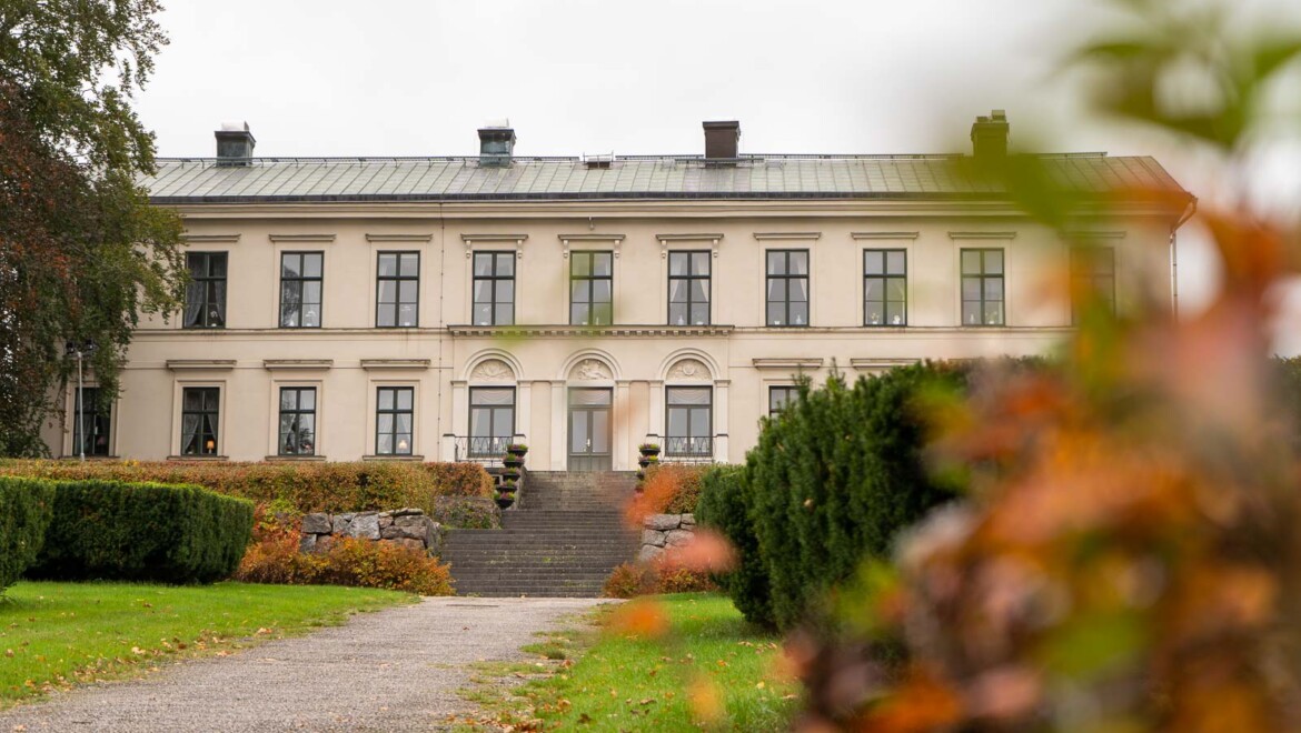 Herrgården i Karlslund med höstlöv i förgrunden.