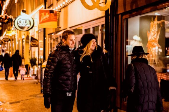 Två personer står tätt intill varandra och tittar in genom en juldekorerat skyltfönster.