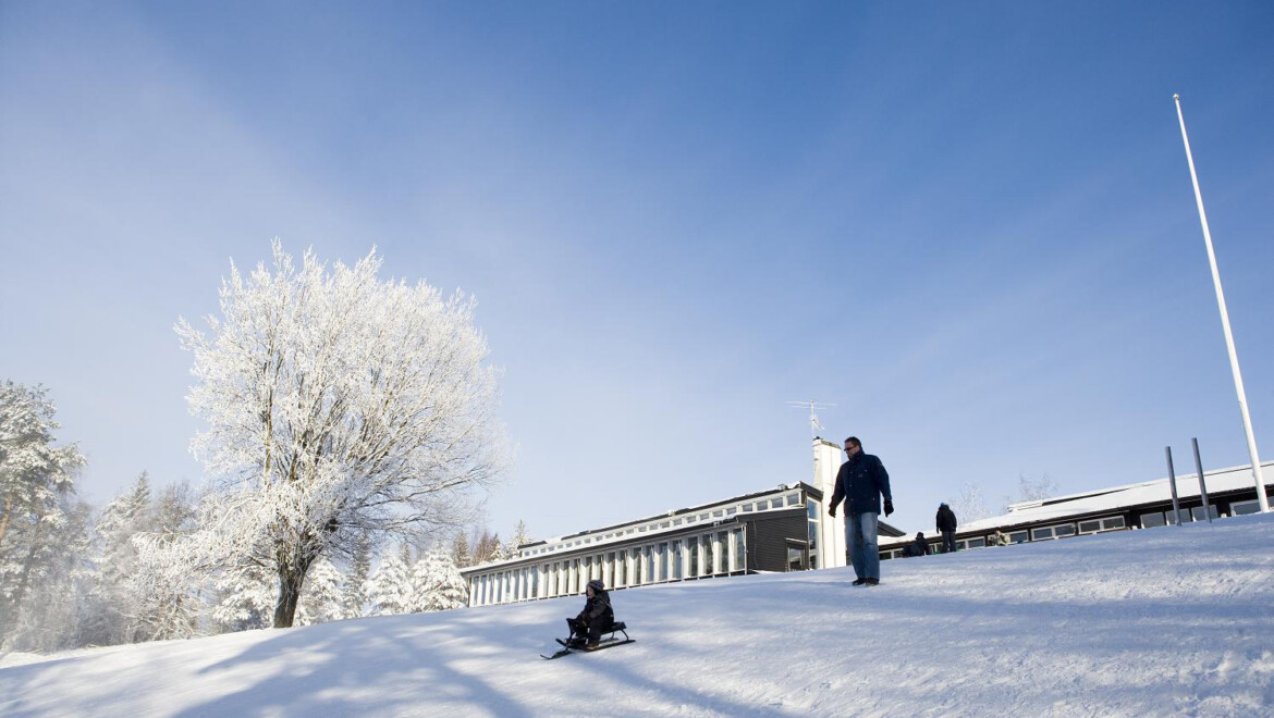 Två personer åker pulka nedför en snötäckt slänt.