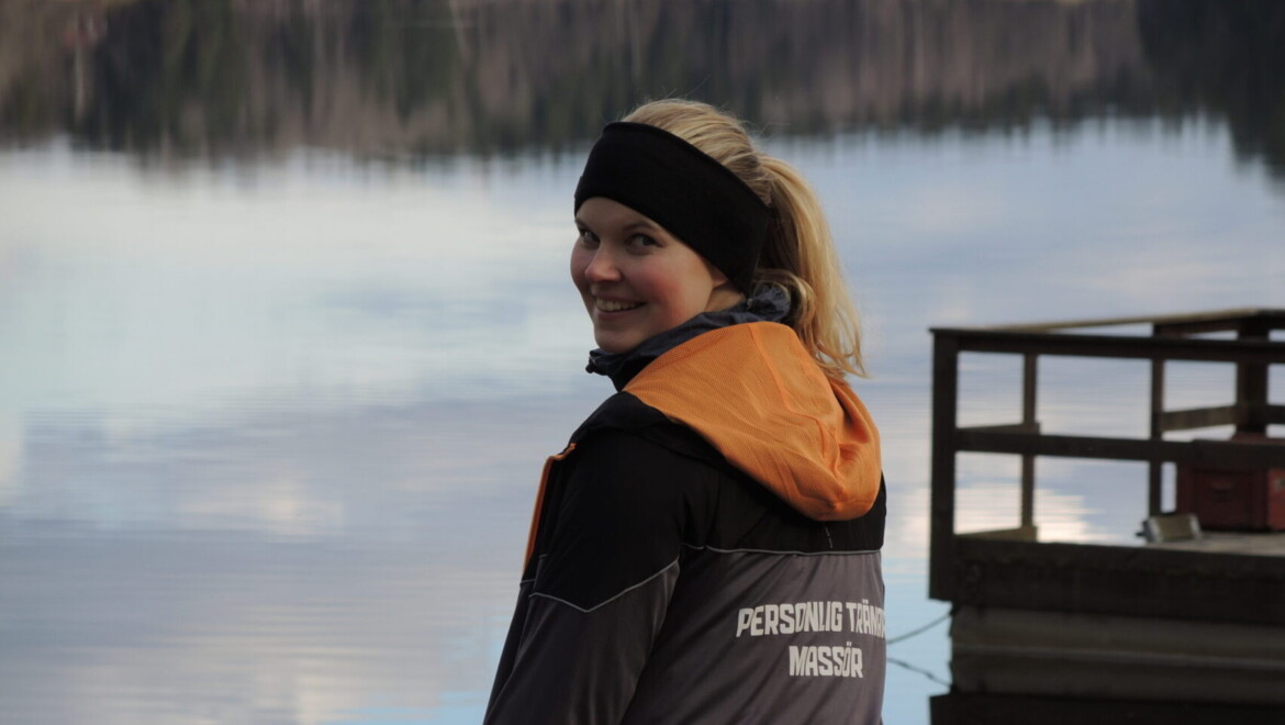Erika Lauri sitter på en bänk och har en jacka med texten Personlig tränare på ryggen.