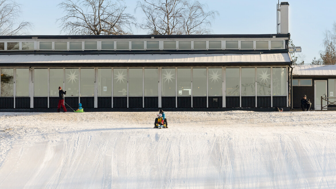 Pulkabacke med stor, inglasad byggnad bakom.
