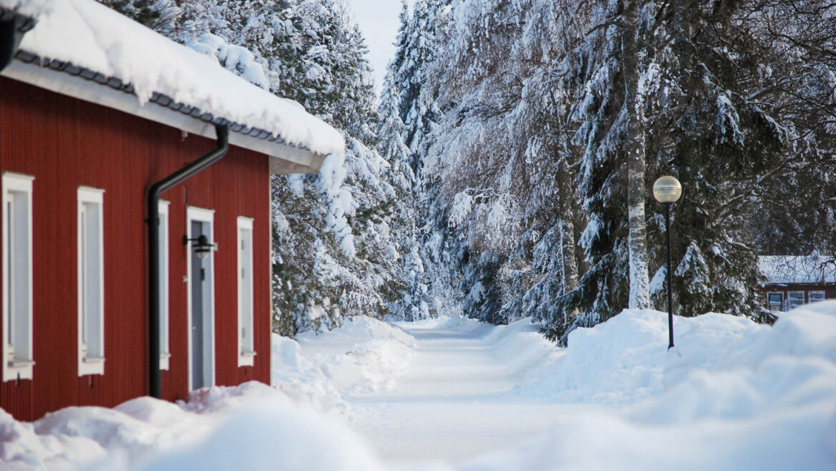 Ett rött trähus omgivet av mycket snö.