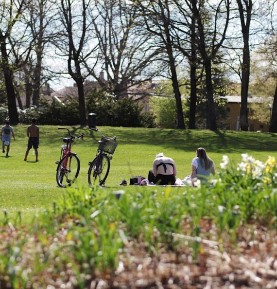 Två personer sitter på gräset och en cykel står parkerad intill.