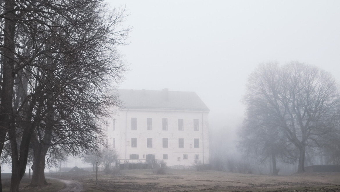 En vit stenbyggnad med dimma omkring.