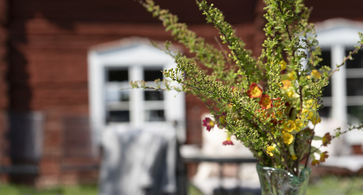 En bukett med gröna och röda blommor i en glasvas.