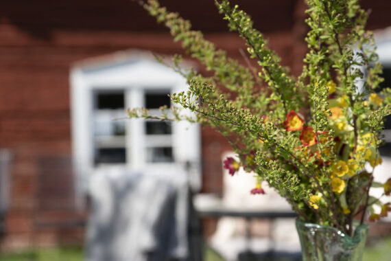 En bukett med gröna och röda blommor i en glasvas.