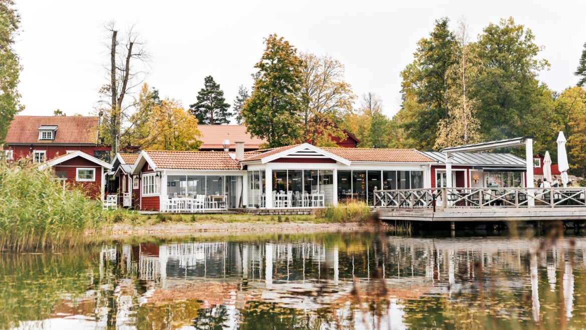 Ett rött hus med vita detaljer som ligger intill vattnet.