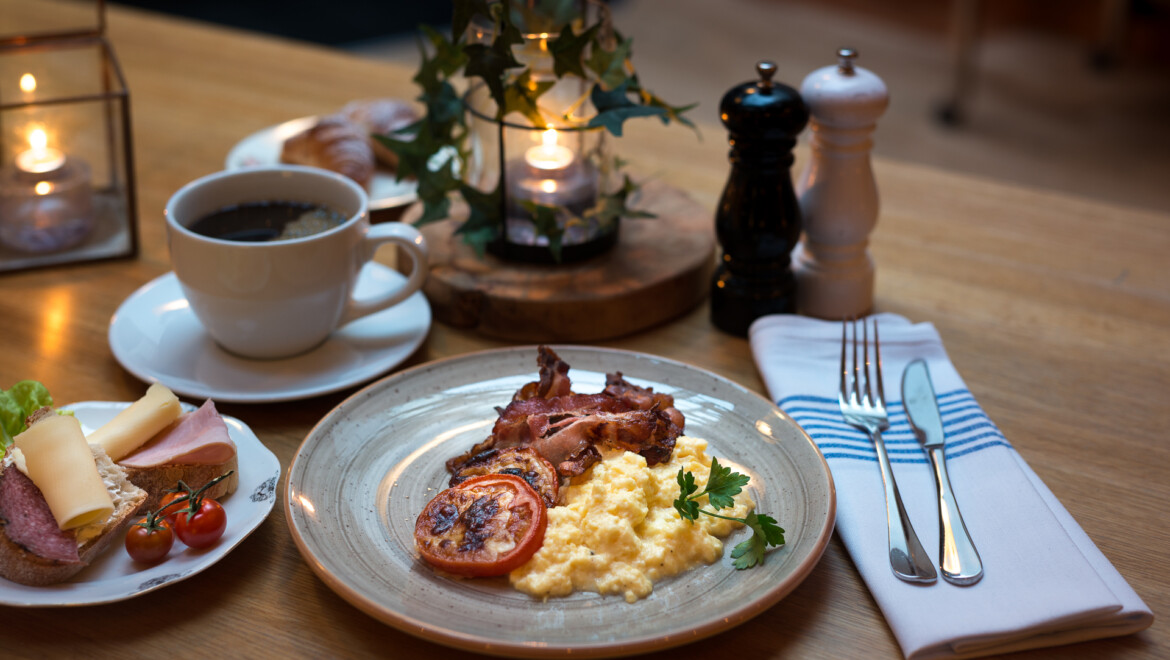 Ett fint framdukat frukostbord, med kaffe, ägg, bacon och tomat.