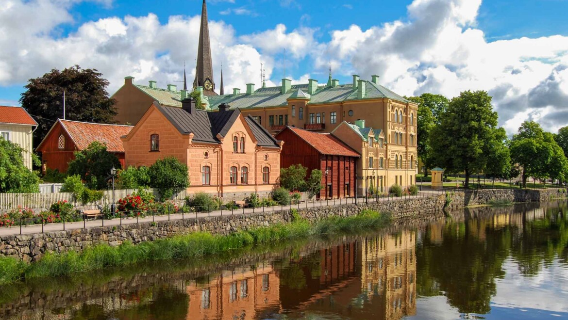 Gamla byggnader och en kyrka i Arboga speglas i en å.
