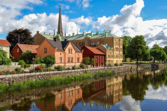 Gamla byggnader och en kyrka i Arboga speglas i en å.