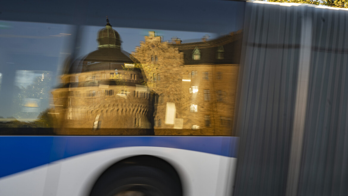 Ett slott reflekteras i fönstret på en blå och vit buss.