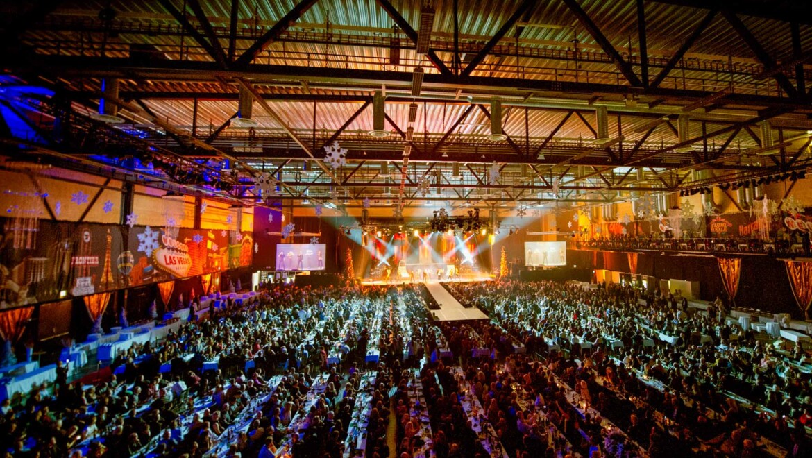 En stor musikarena med långbord och många sittande människor.