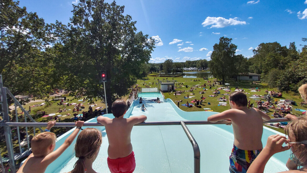 Barn står med ryggen till och tittar ut över en vattenrutschbana.