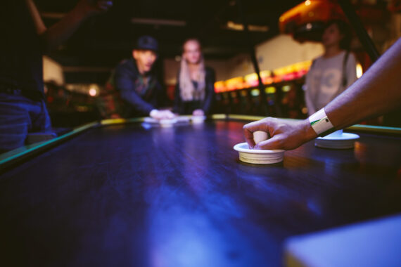 Young friends playing air hockey game