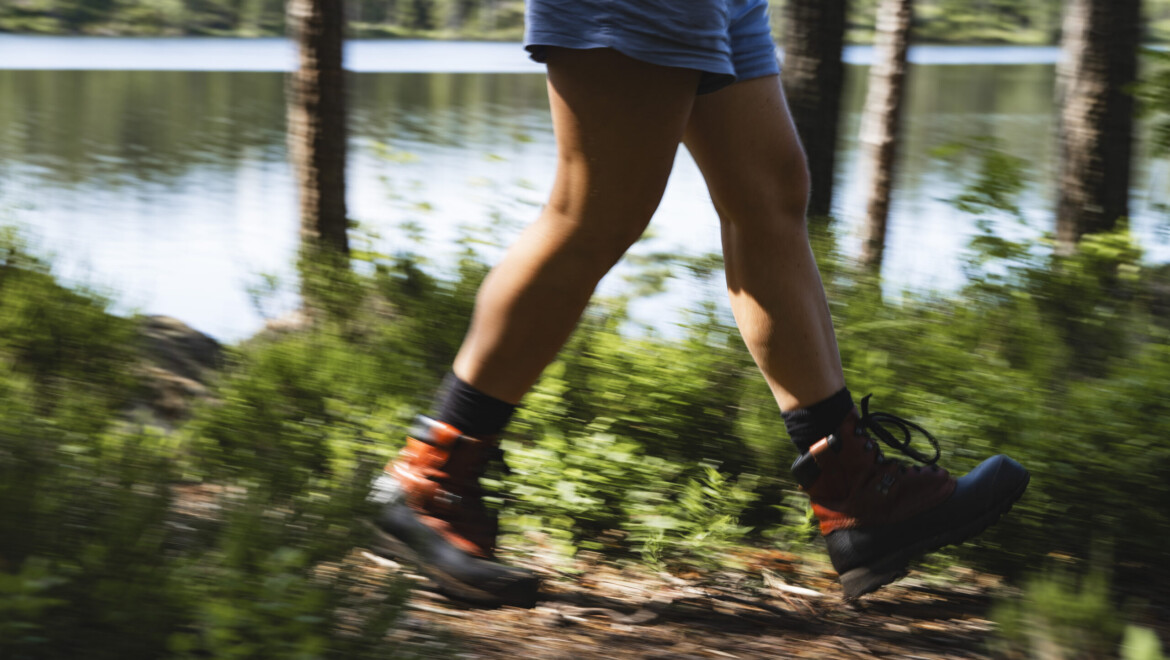 Två ben som vandrar genom Kilsbergens stigar, med träd och en sjö i bakgrund.