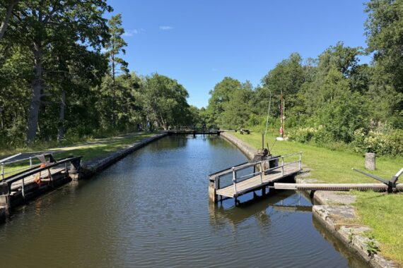En kanal med slussar omringas av grönska och klarblå himmel.